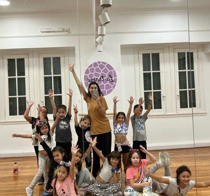 Chicos y chicas festejando con los brazos arriba en una de las salas del estudio, con el logo de La Trama en la pared.