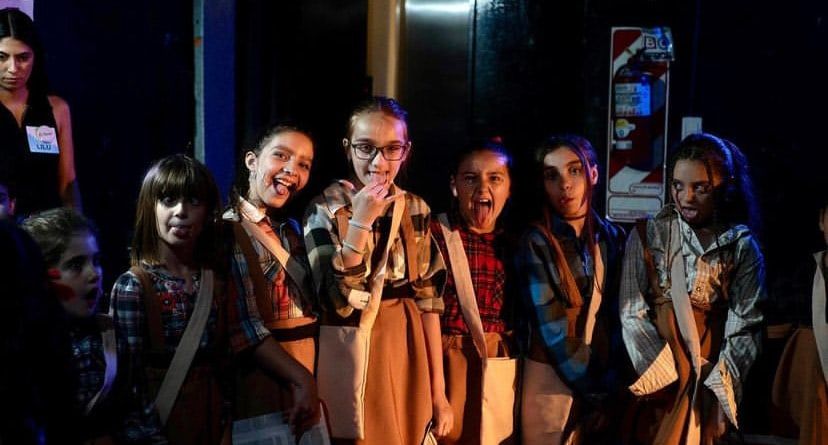 Grupo de alumnas con vestuario en escena, iluminadas desde arriba.