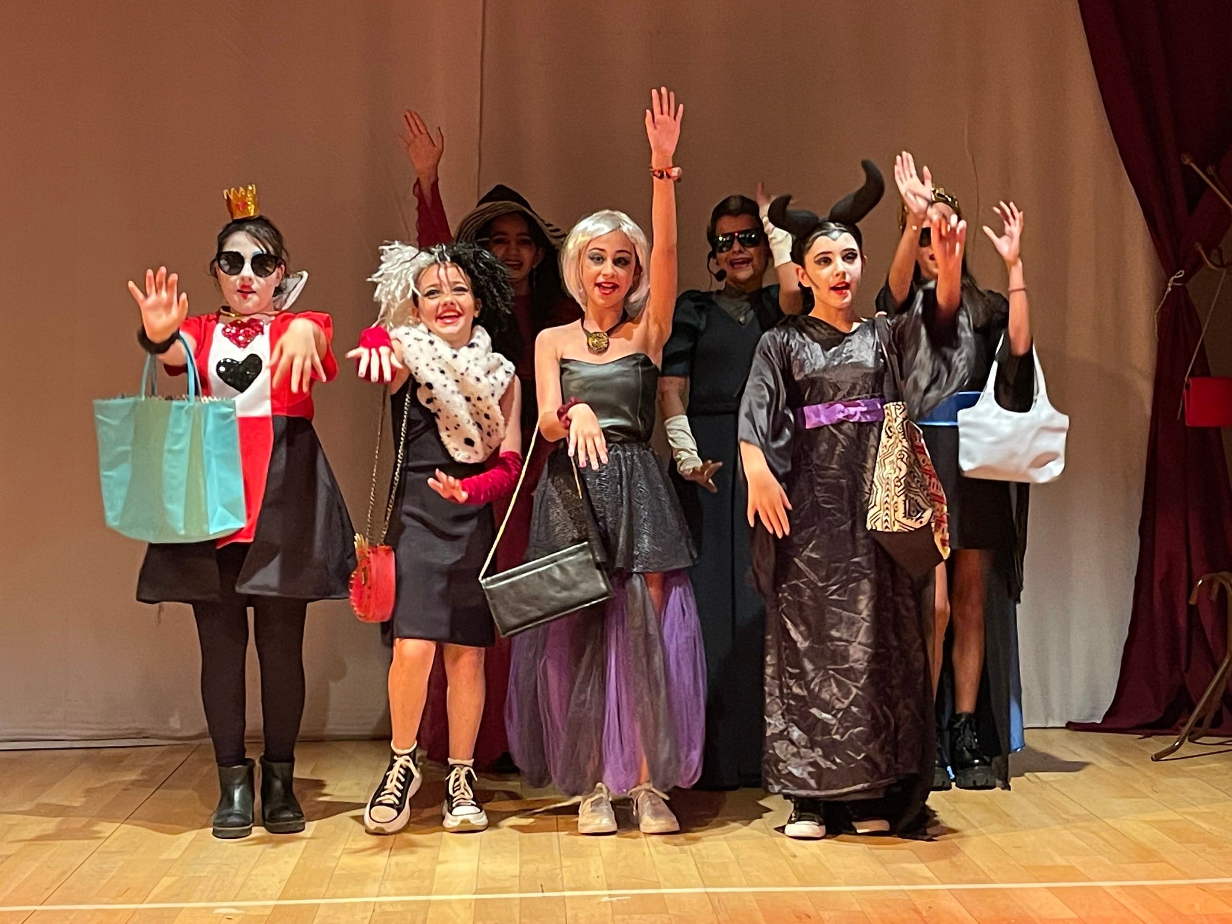 Grupo de chicas caracterizadas como villanas de cuentos, con maquillaje y vestuario, sobre el escenario del estudio.