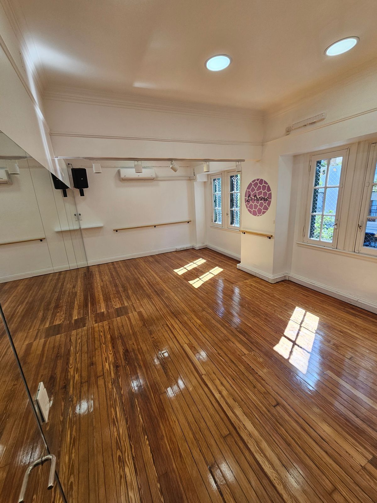 Sala Aida: piso de madera, espejos, ventanales y el logo de La Trama en la pared.